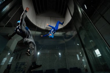 Erkek bir eğitmen bir kadına rüzgar tünelinde uçmayı öğretir. Serbest düşüş simülatörü