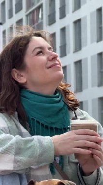 Beyaz kadın Jack Russell Terrier köpeğini gezdirirken kahve içiyor.