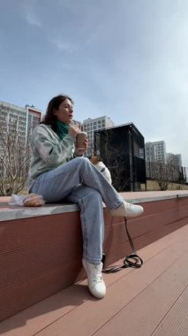 Beyaz kadın kruvasan yiyip kahve içerken Jack Russell terrier köpeğini gezdiriyordu.