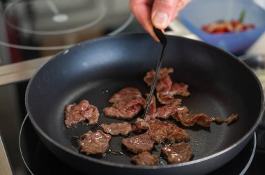 Şef kızartma tavasında dana eti kızartıyor.