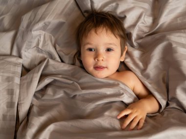 Beyaz tenli şirin bir çocuğun yatakta yatışının üst görüntüsü.
