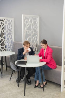 Meslektaşlar dizüstü bilgisayarda oturup iş konuşuyorlar.