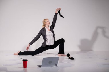 Beyaz arka planda iş elbisesiyle dans eden çıplak ayaklı balerin.