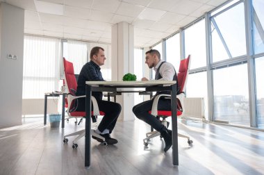 İki beyaz adam bir iş toplantısında iletişim kuruyor.