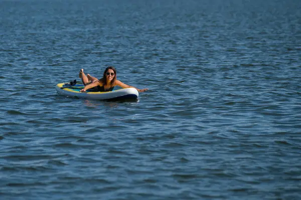 SUP panosunda poz veren beyaz bir kadın. Yaz sporu