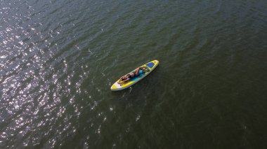 Gölde SUP sörf tahtası süren beyaz bir kadın. Yukarıdan bak. Yaz sporu