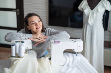 Beyaz kadın evde bir elbise dikiyor. Bir terzinin çalışma alanı.