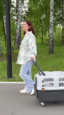 Beyaz kadın köpekle seyahat ediyor. Sahibi Jack Russell Terrier 'ı gezdirir ve güvenli bir yolculuk için kafesi taşır..