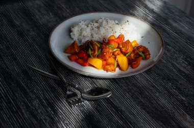 Tatlı ve ekşi soslu domuz eti ve tabakta haşlanmış pirinç.