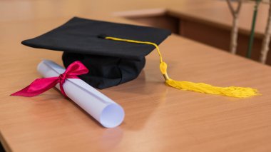 Mezuniyet şapkası ve diploma masada.
