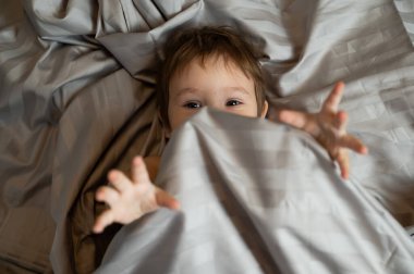 Beyaz tenli şirin bir çocuğun yatakta yatışının üst görüntüsü.