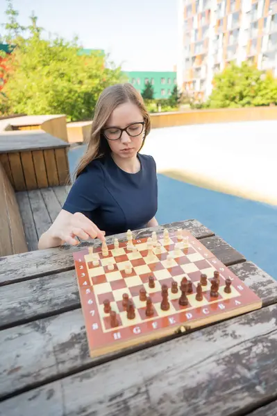 Beyaz kadın dışarıda satranç oynuyor.