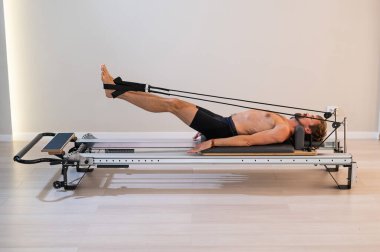 Reformcu üzerinde pilates yapan bir adam.