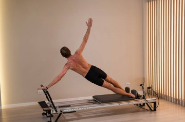 Reformcu üzerinde pilates yapan bir adam.