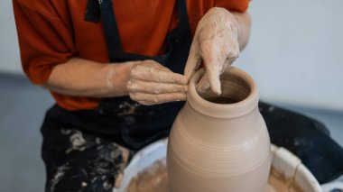 Çömlekçi elleriyle çömlekçi çarkında seramik vazo yaparken.
