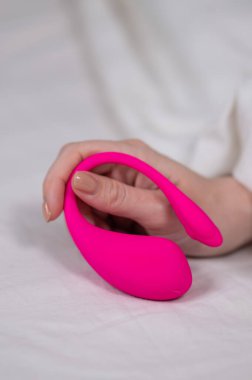 Yatakta uzanırken kavisli pembe vibratör tutan kadın.