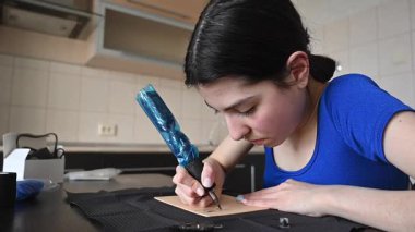 Yapay deri üzerinde dövme pratiği yapan genç bir kadın.