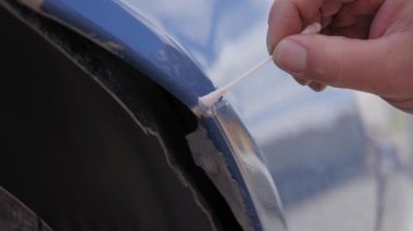 Bir adam, bir araba cesedindeki paslı bir çiziği gizliyor. Pas dönüştürücü