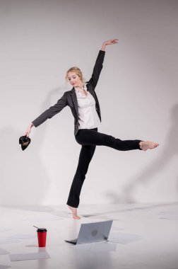 Beyaz arka planda iş elbisesiyle dans eden çıplak ayaklı balerin.