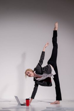 Beyaz arka planda iş elbisesiyle dans eden çıplak ayaklı balerin.