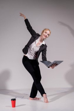 Beyaz arka planda iş elbisesiyle dans eden çıplak ayaklı balerin.