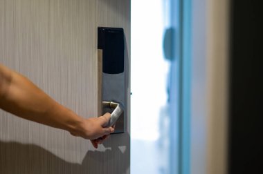 Bir kadın kartla elektronik kilidi açar ve bir otel odasına girer.