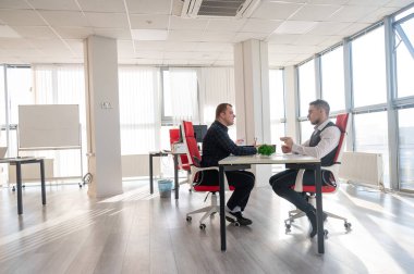 İki beyaz adam bir iş toplantısında iletişim kuruyor.