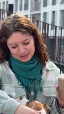 Beyaz kadın Jack Russell Terrier köpeğini gezdirirken kahve içiyor.