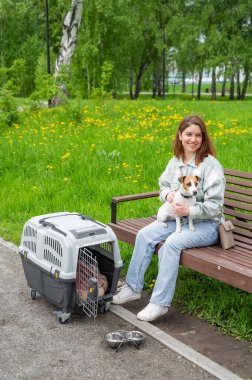 Sahibi Jack Russell Terrier ile birlikte güvenli bir yolculuk için bankta oturuyor.