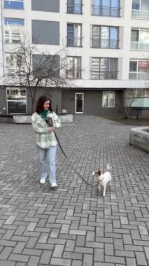 Beyaz kadın Jack Russell Terrier köpeğini yürüyüşe çıkarıyor.