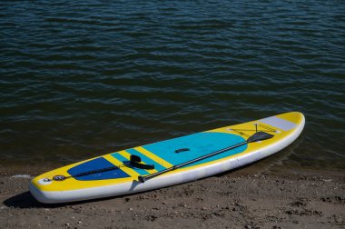 Kumlu bir plajda SUP tahtası. Yaz sporu