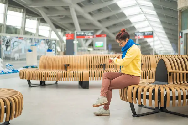 Maskeli beyaz kadın halka açık bir yerde akıllı saat kullanıyor.