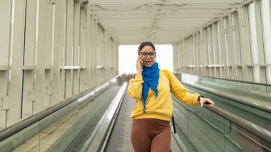 Mutlu kadın travertörün üzerinde duruyor ve cep telefonuyla konuşuyor..