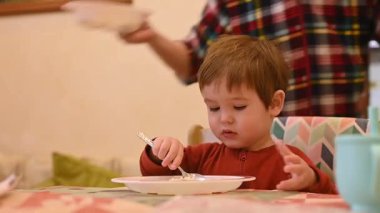 Şirin bir çocuk tek başına yulaf lapası yiyor.