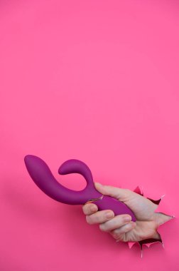 Pembe kağıttan yapılmış ahududulu seks oyuncağıyla takılan bir kadın eli.
