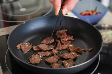 Şef kızartma tavasında dana eti kızartıyor.
