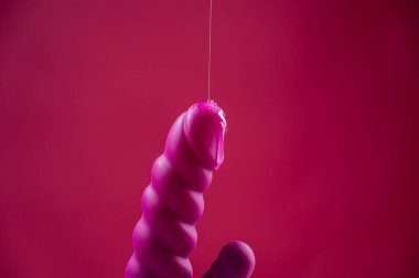 Lube pouring on pink dildo on pink background