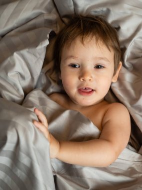 Beyaz tenli şirin bir çocuğun yatakta yatışının üst görüntüsü.