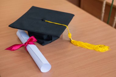 Mezuniyet şapkası ve diploma masada.
