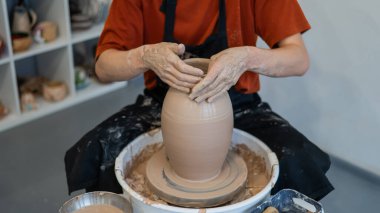 Çömlekçi elleriyle çömlekçi çarkında seramik vazo yaparken.
