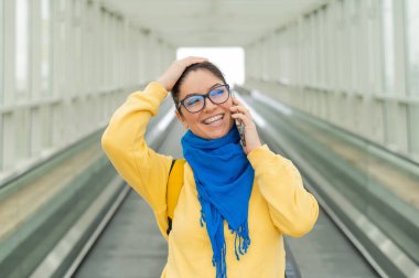 Mutlu kadın travertörün üzerinde duruyor ve cep telefonuyla konuşuyor..