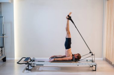 Reformcu üzerinde pilates yapan bir adam.