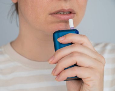 Elektronik sigara içen beyaz bir kadın. Tütün ısıtma sistemi