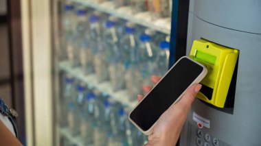 Cep telefonlu Modern Otomat Ödemesi. Bir kadın self-servis makinesinden bir şişe su alır.