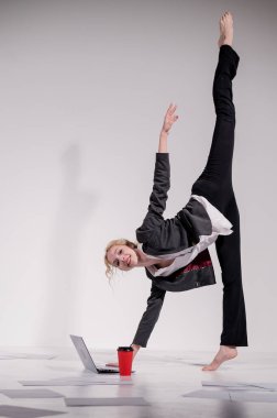 Beyaz arka planda iş elbisesiyle dans eden çıplak ayaklı balerin.