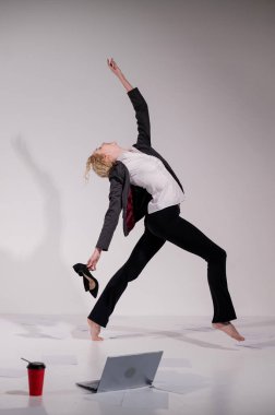 Beyaz arka planda iş elbisesiyle dans eden çıplak ayaklı balerin.