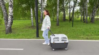 Beyaz kadın köpekle seyahat ediyor. Sahibi Jack Russell Terrier 'ı gezdirir ve güvenli bir yolculuk için kafesi taşır..