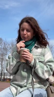 Beyaz kadın Jack Russell Terrier köpeğini gezdirirken kahve içiyor.