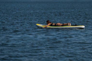 SUP panosunda poz veren beyaz bir kadın. Yaz sporu