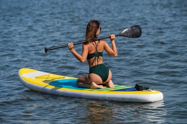 SUP panosunda poz veren beyaz bir kadın. Yaz sporu